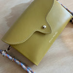 mustard leather handbag with a rope strap on a wooden surface