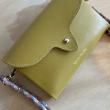 mustard leather handbag with a rope strap on a wooden surface