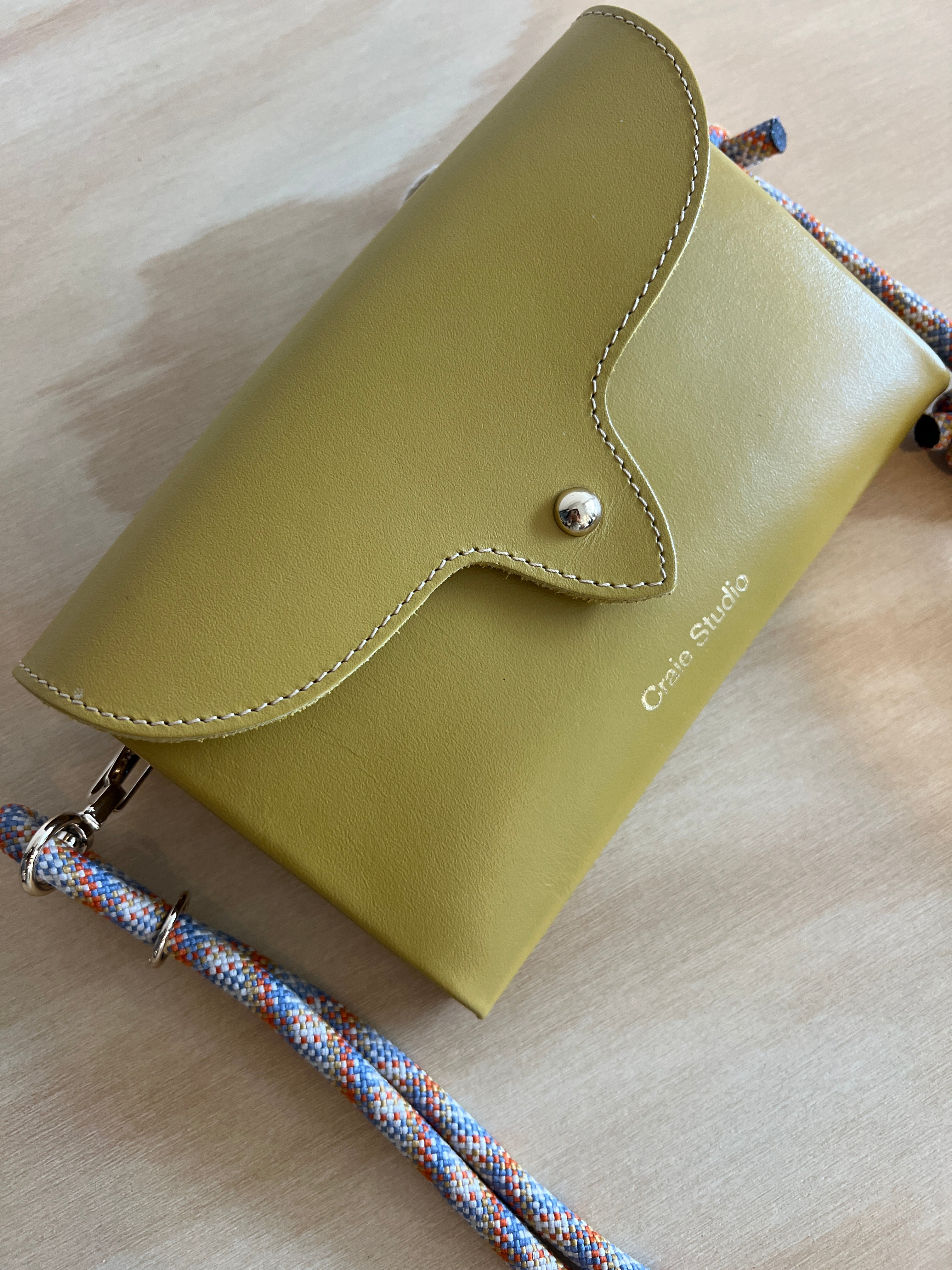 mustard leather handbag with a rope strap on a wooden surface