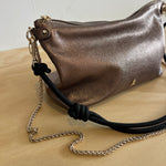 Metallic handbag with a chain strap on a light wooden surface