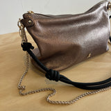 Metallic handbag with a chain strap on a light wooden surface