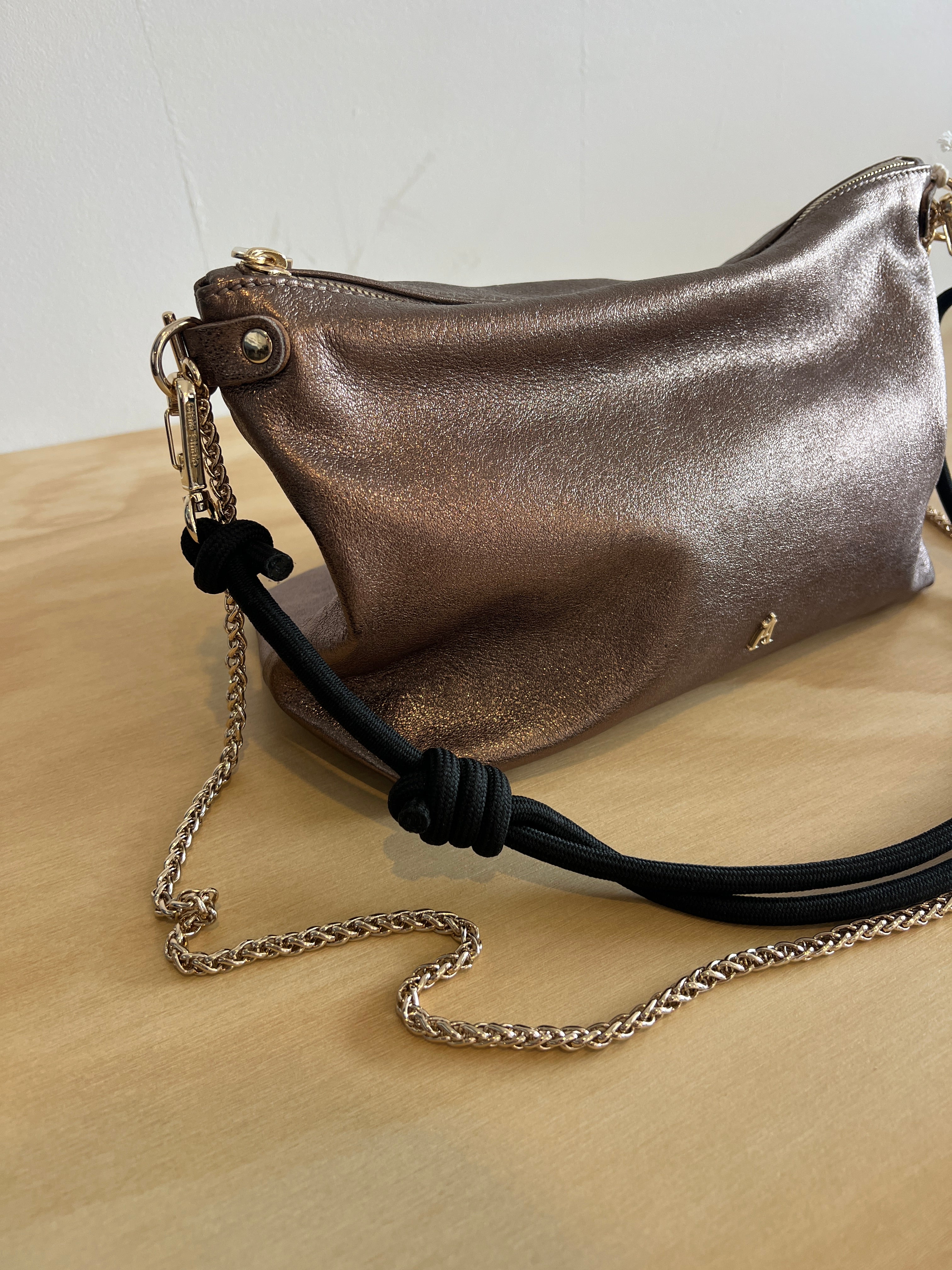 Metallic handbag with a chain strap on a light wooden surface
