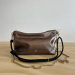 Metallic handbag with a chain strap on a light wooden surface