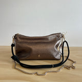 Metallic handbag with a chain strap on a light wooden surface