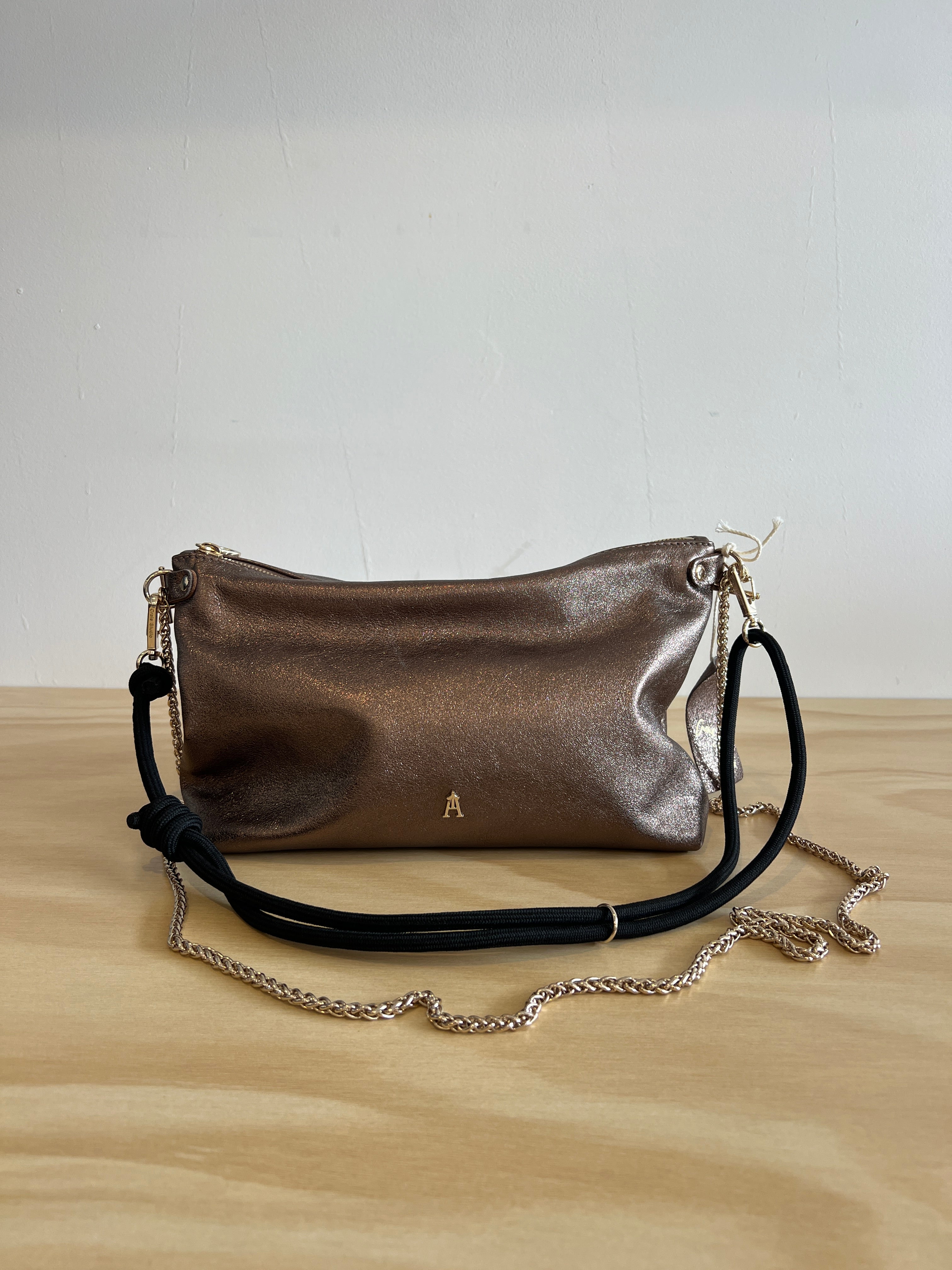 Metallic handbag with a chain strap on a light wooden surface