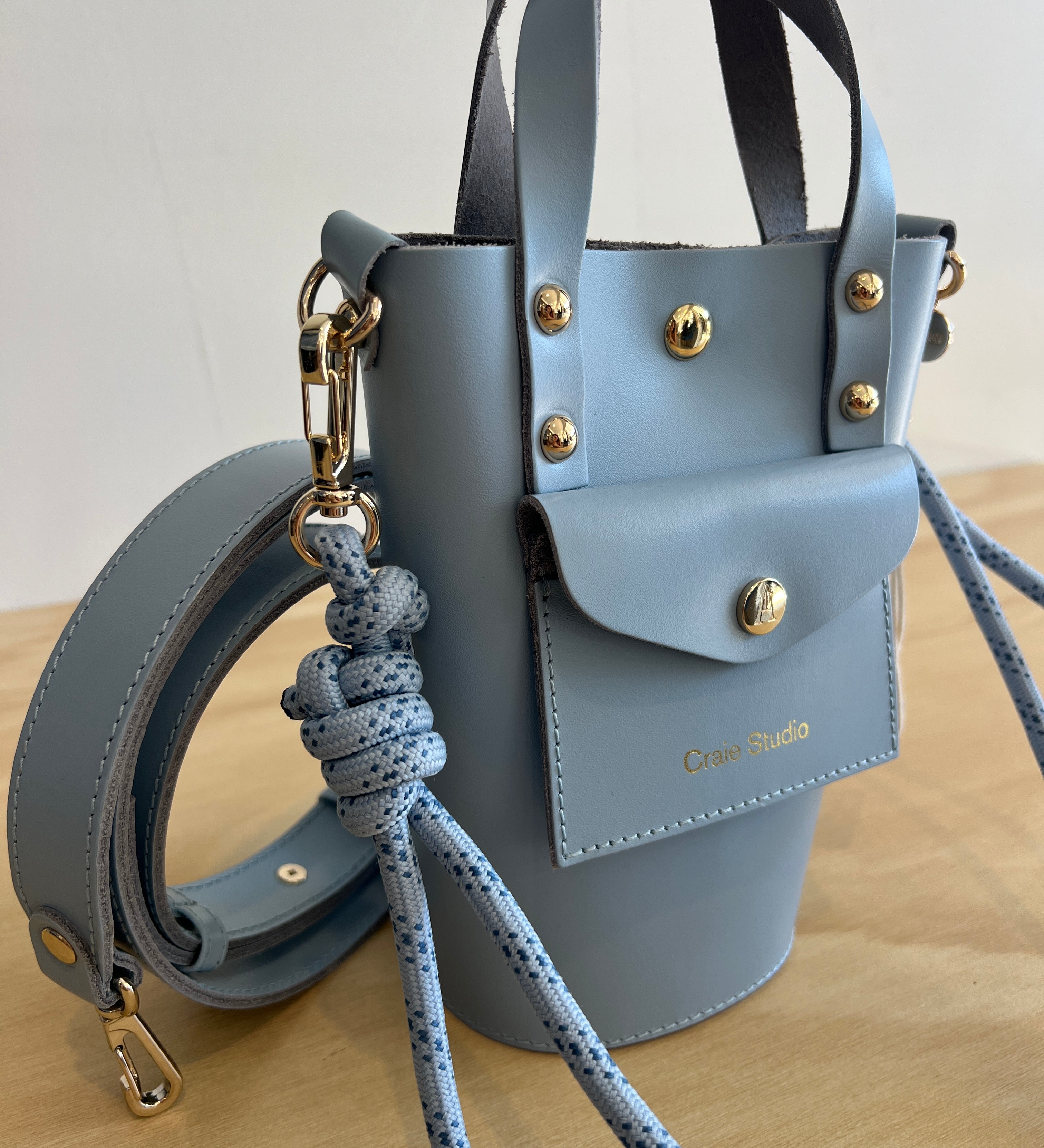 Light blue leather handbag with gold accents on a neutral background