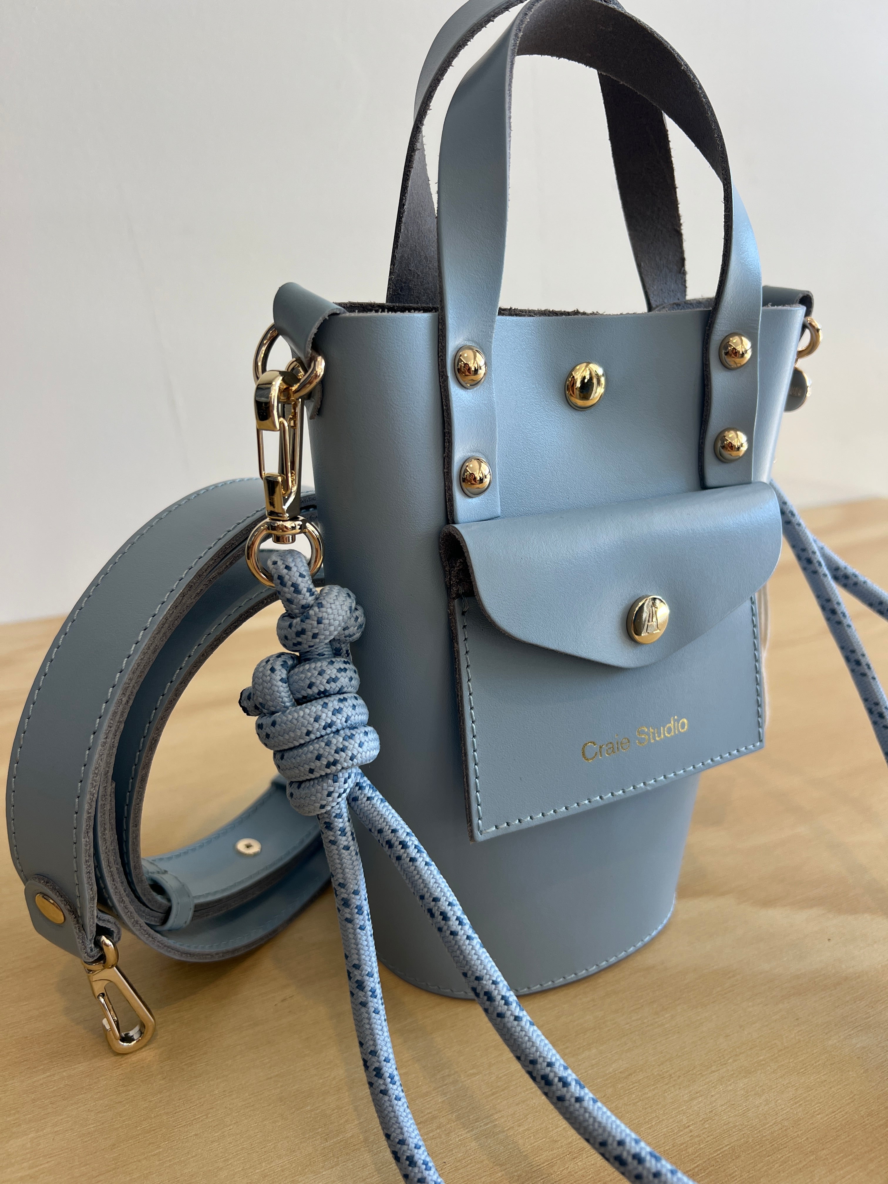 Light blue leather handbag with gold accents on a neutral background