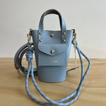 Light blue handbag with gold accents on a wooden surface
