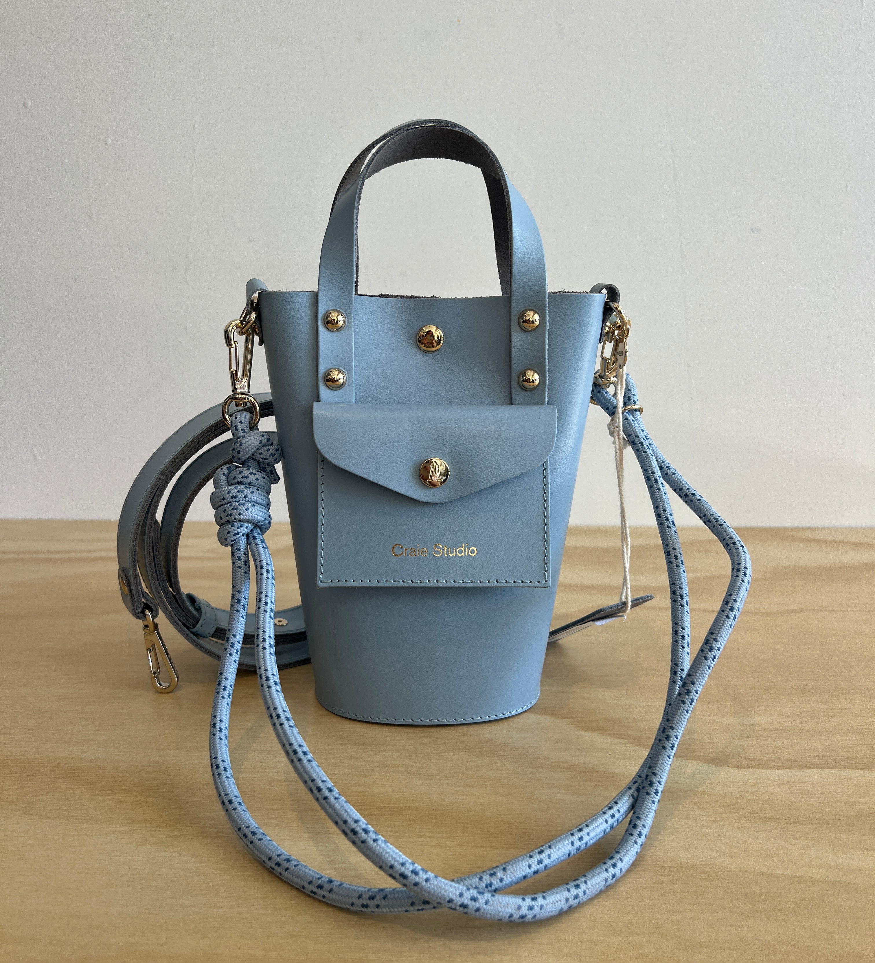 Light blue handbag with gold accents on a wooden surface