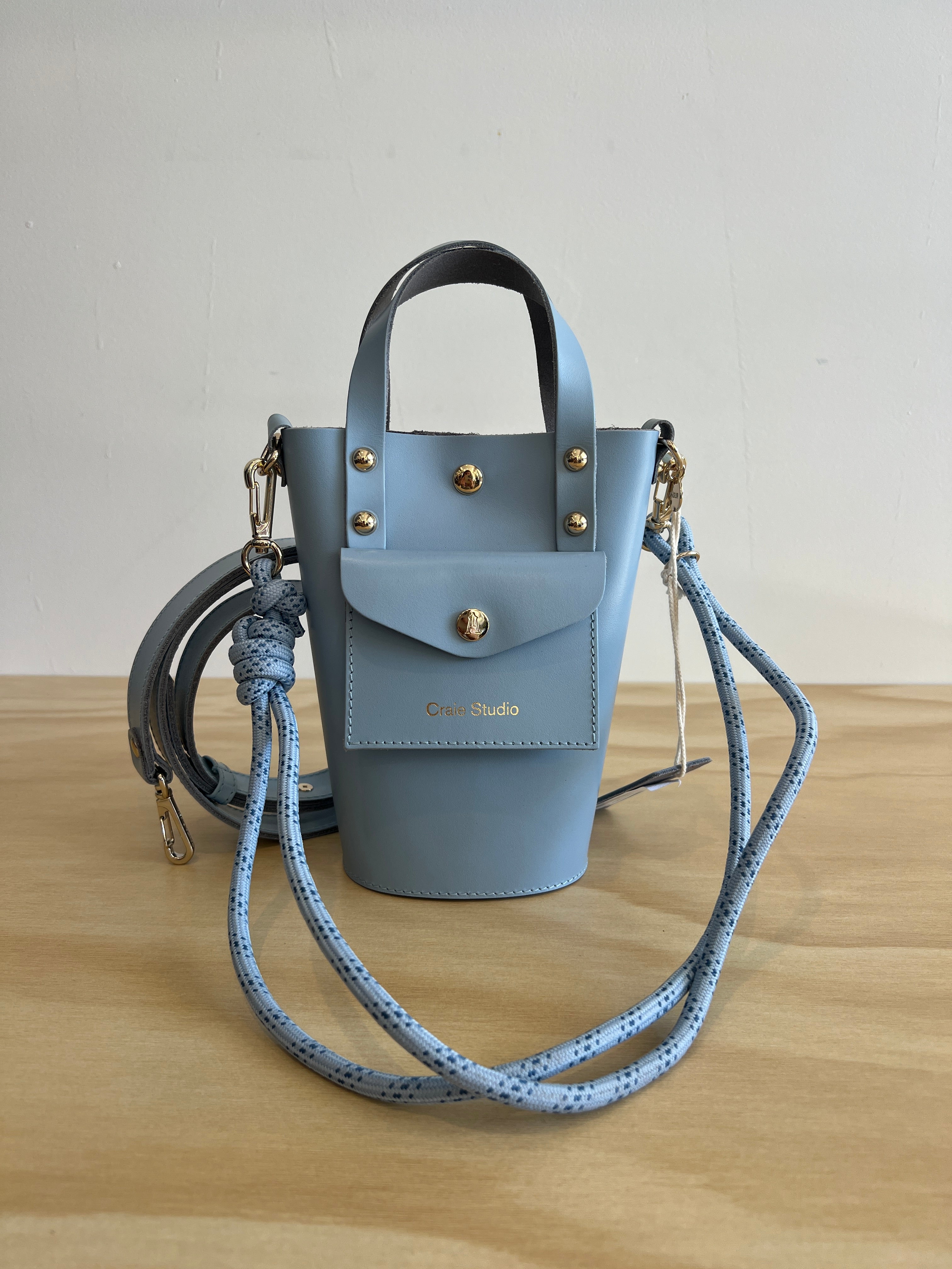 Light blue handbag with gold accents on a wooden surface