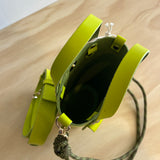 Lime green handbag with a strap on a wooden surface