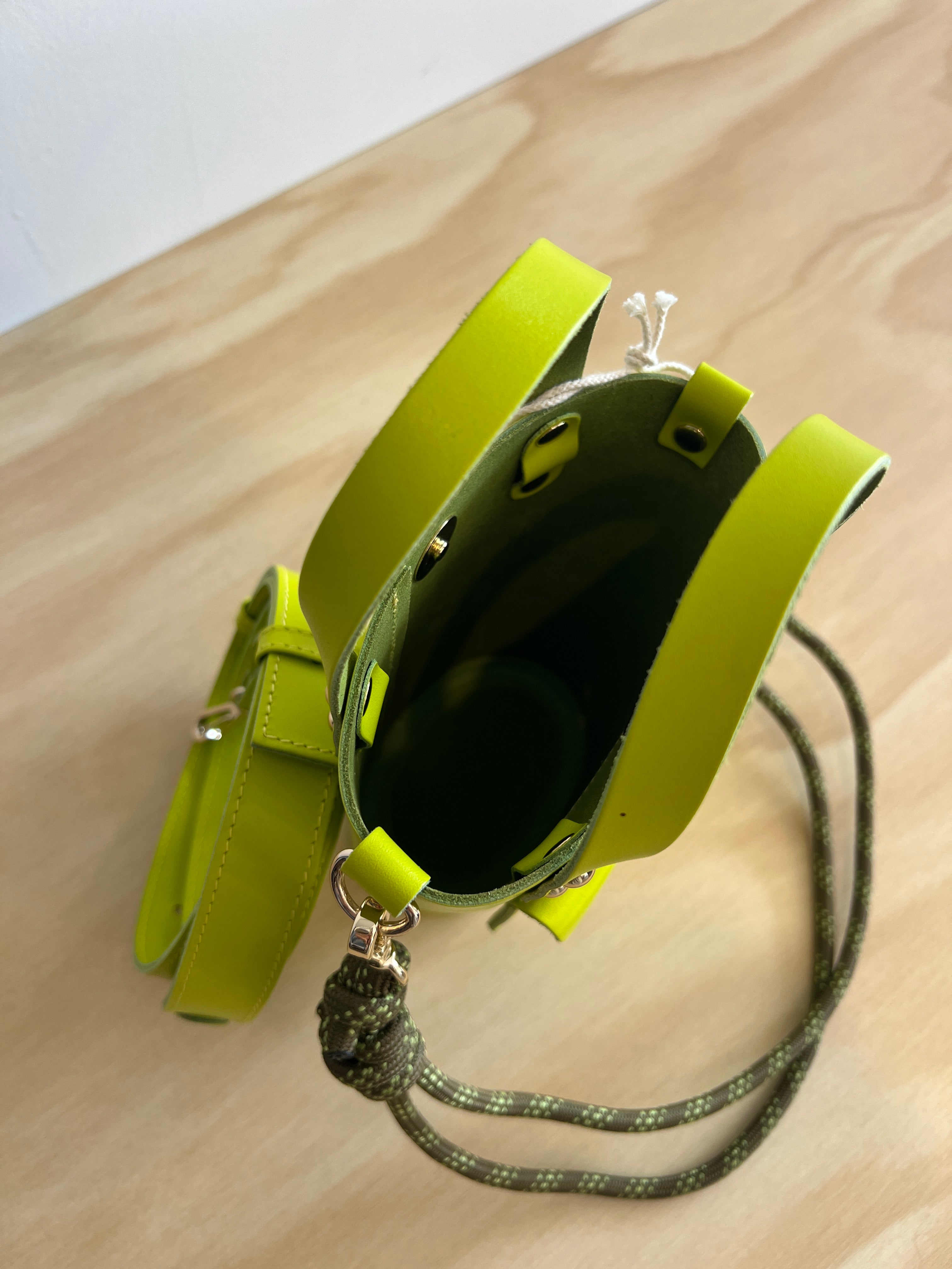 Lime green handbag with a strap on a wooden surface