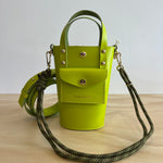 Green handbag with a strap on a light wooden surface
