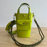 Green handbag with a strap on a light wooden surface