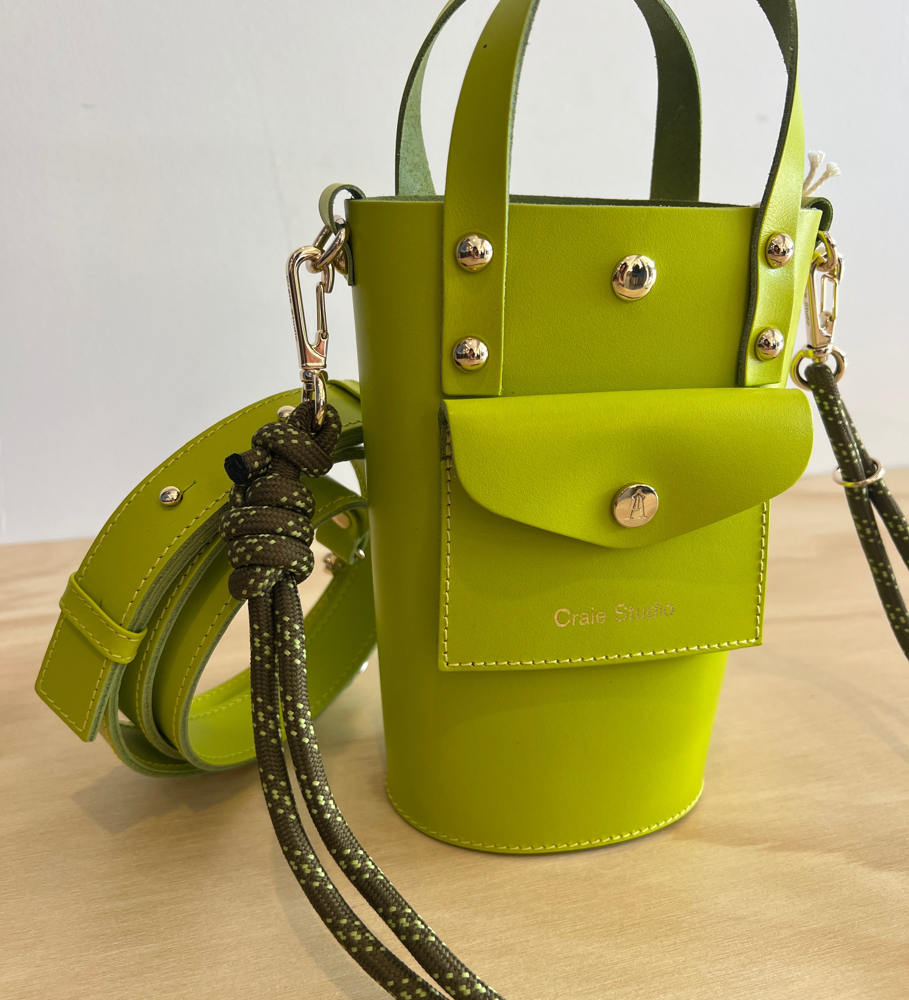 Green handbag with a strap on a wooden surface