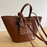 Brown leather handbag with a strap on a light background