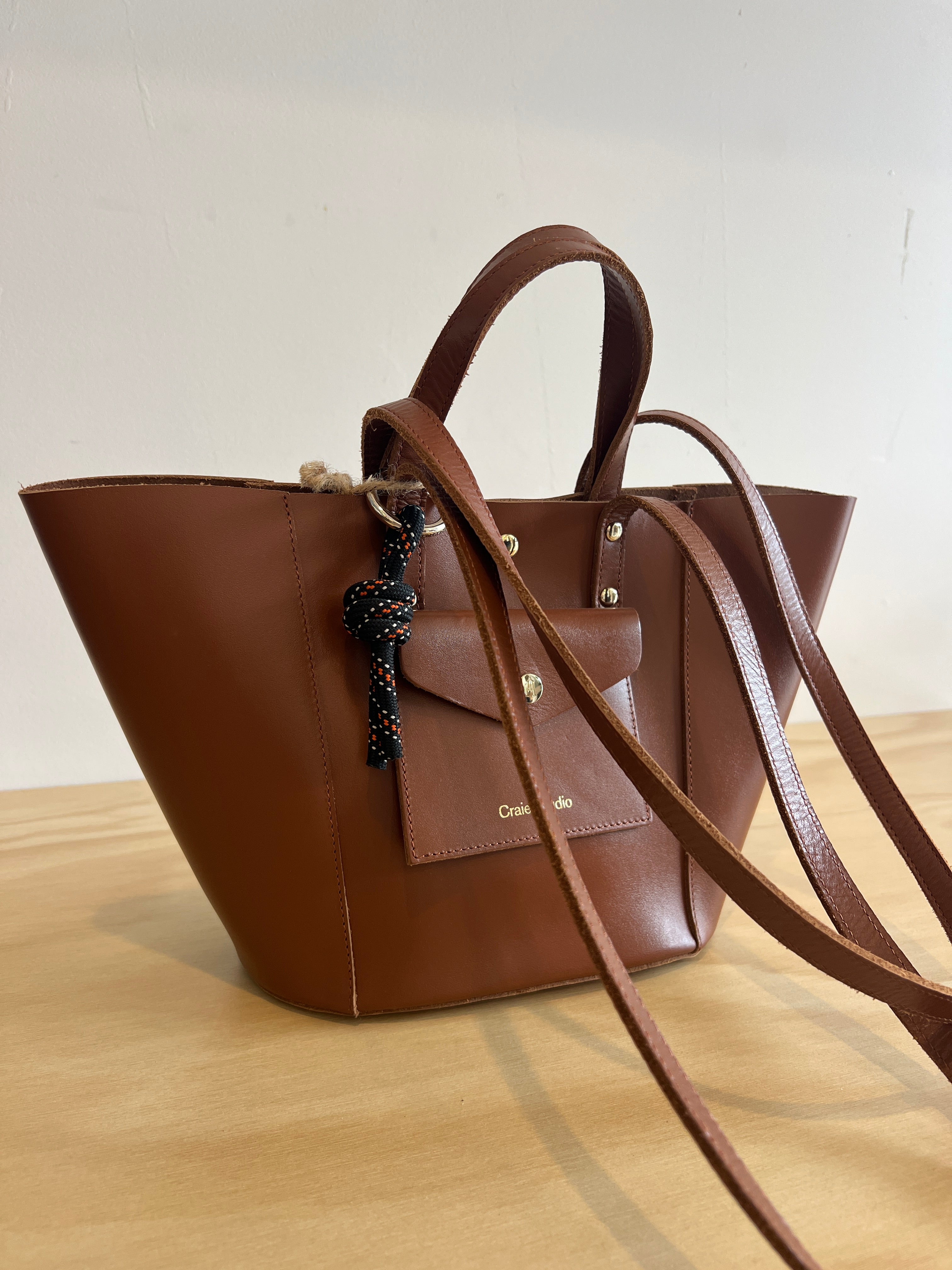 Brown leather handbag with a strap on a light background