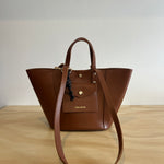Brown leather handbag on a light wooden surface