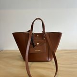 Brown leather handbag on a light wooden surface