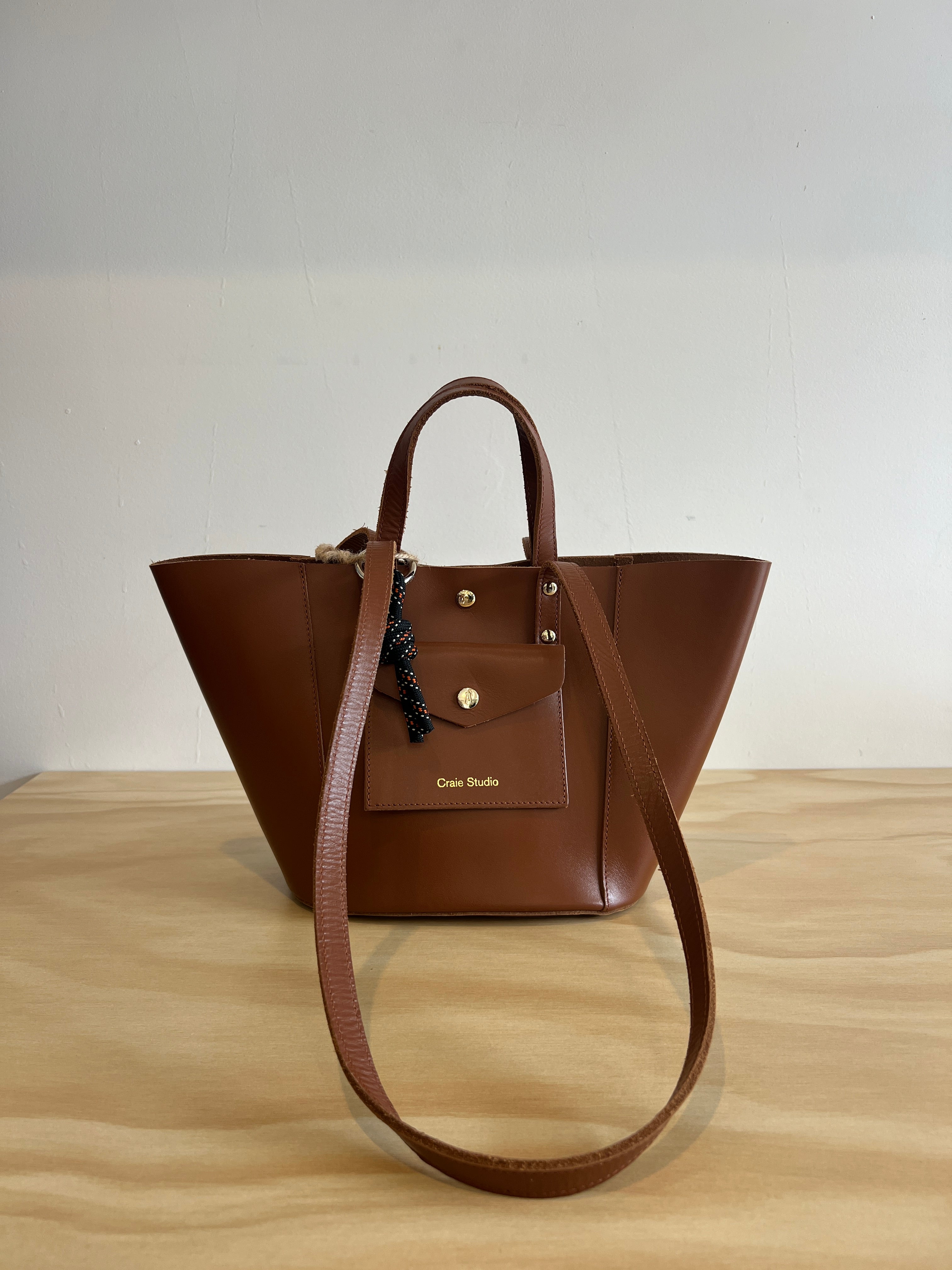 Brown leather handbag on a light wooden surface