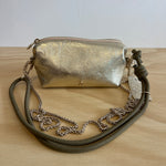 Gold metallic handbag with a chain strap on a wooden surface