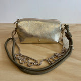 Gold metallic handbag with a chain strap on a wooden surface