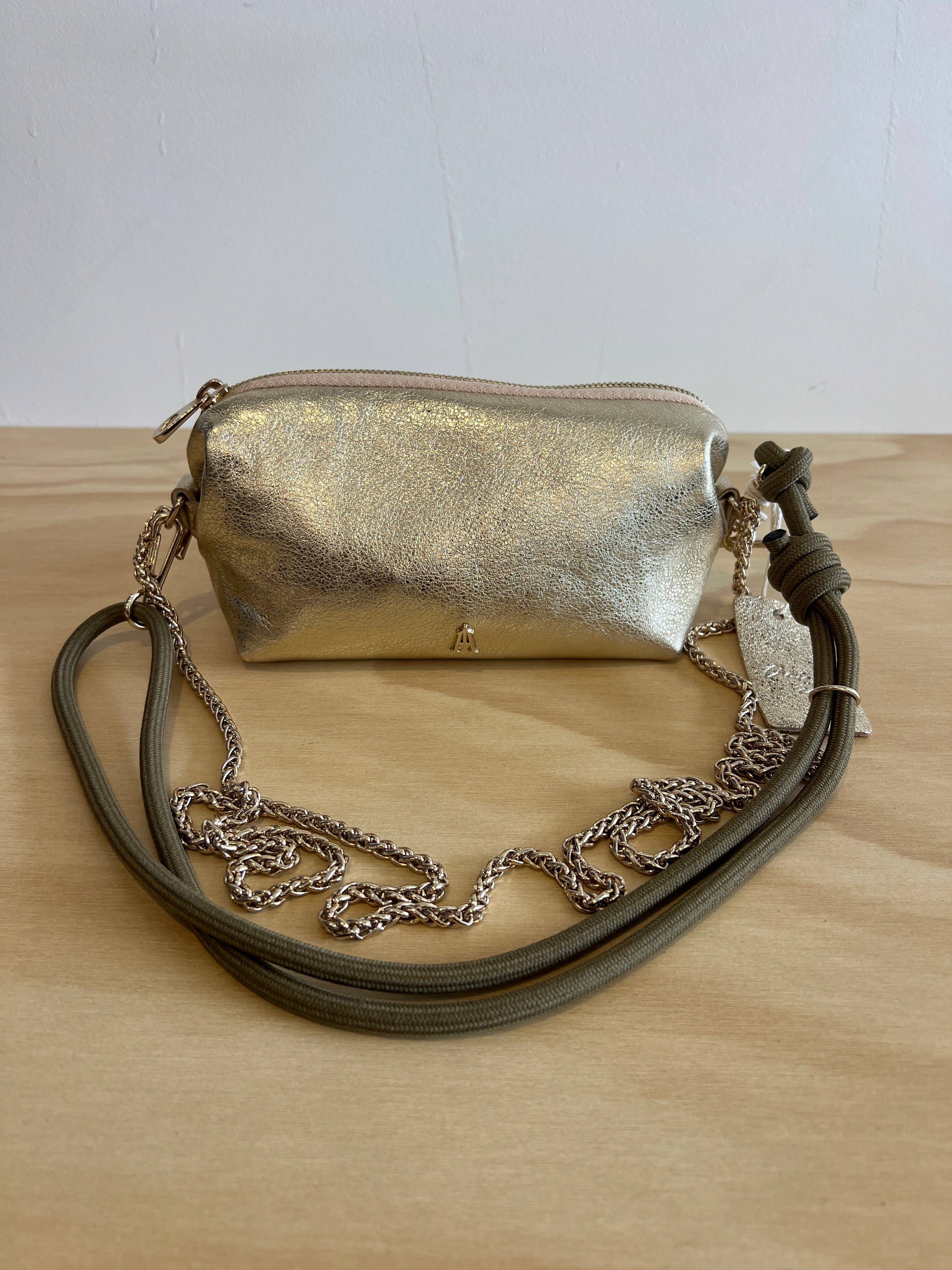 Gold metallic handbag with a chain strap on a wooden surface