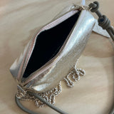 Gold metallic clutch bag with chain detail on a beige surface