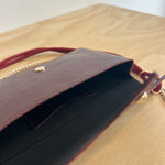 Close-up of a brown leather clutch bag with gold accents on a beige background