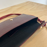 Close-up of a brown leather clutch bag with gold accents on a beige background