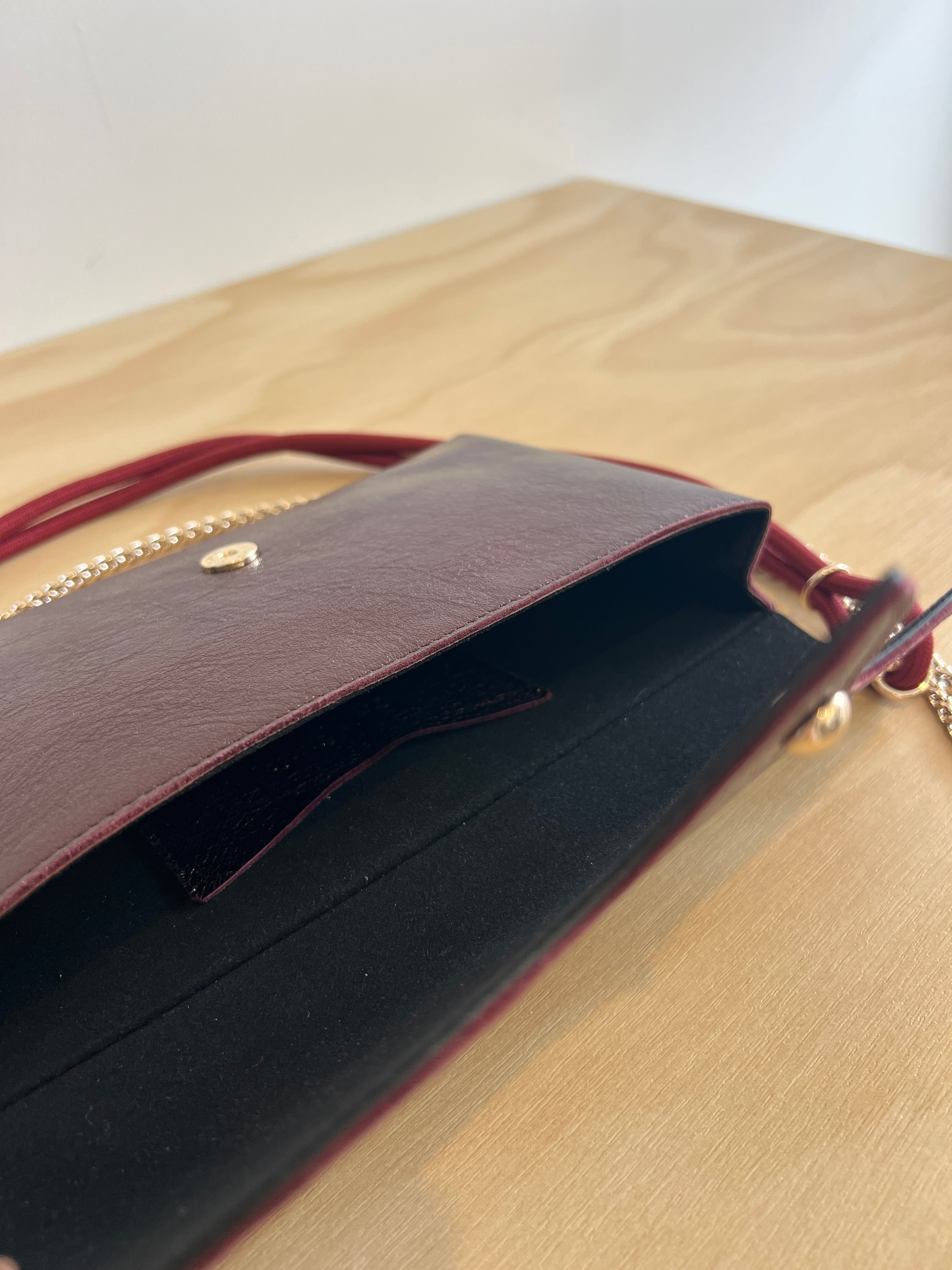 Close-up of a brown leather clutch bag with gold accents on a beige background
