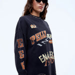 Person wearing a navy blue sweatshirt with multiple brand logos on a white background