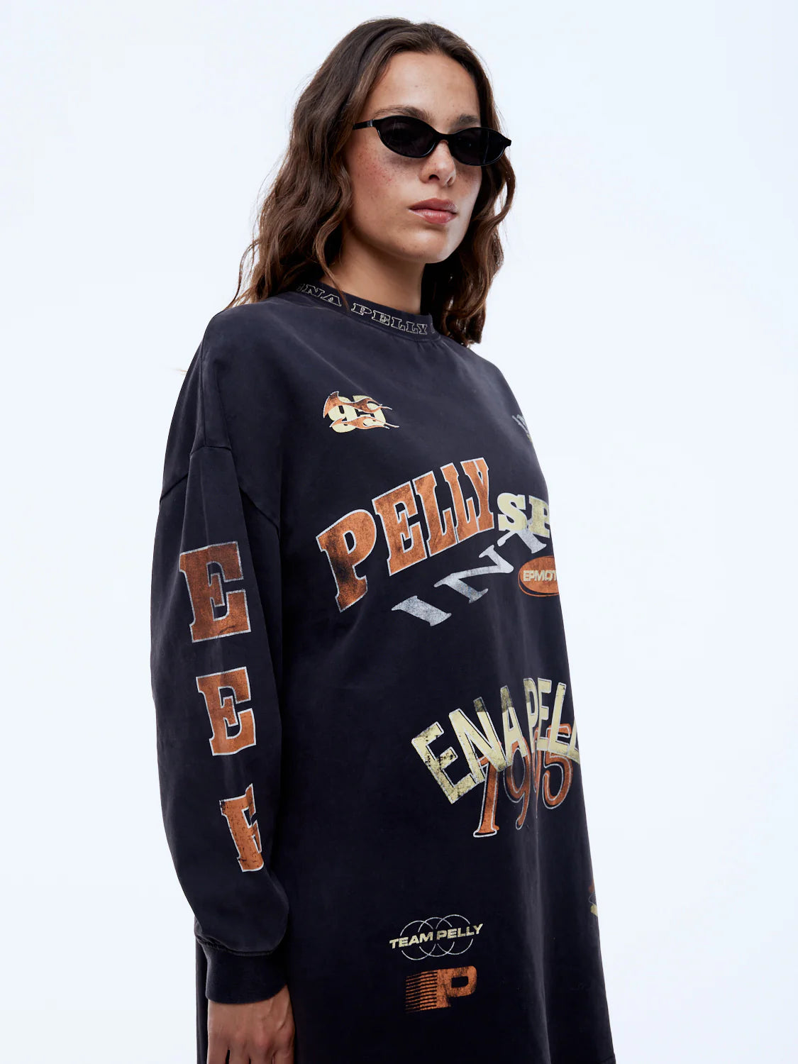 Person wearing a navy blue sweatshirt with multiple brand logos on a white background