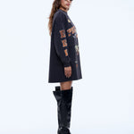 Woman wearing a black oversized sweatshirt with text and black knee-high boots on a white background
