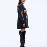 Woman wearing a black oversized sweatshirt with text and black knee-high boots on a white background