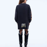 Person wearing a black dress with text and black boots on a white background