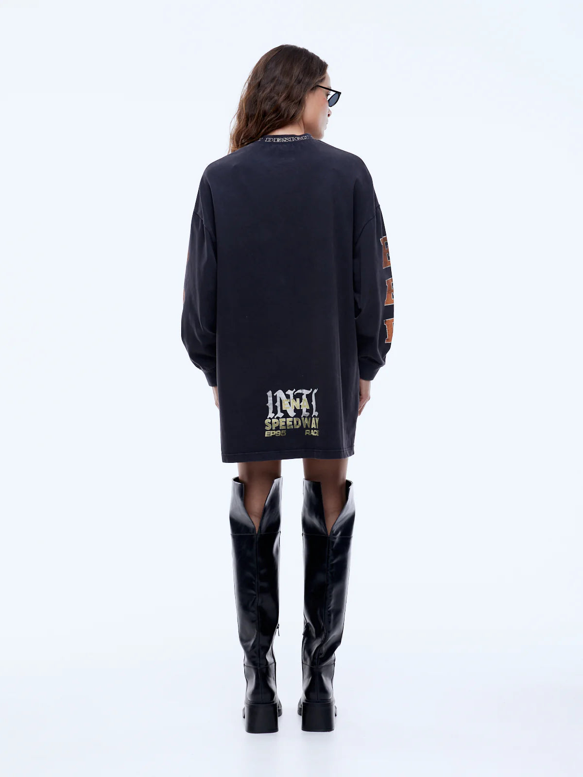 Person wearing a black dress with text and black boots on a white background