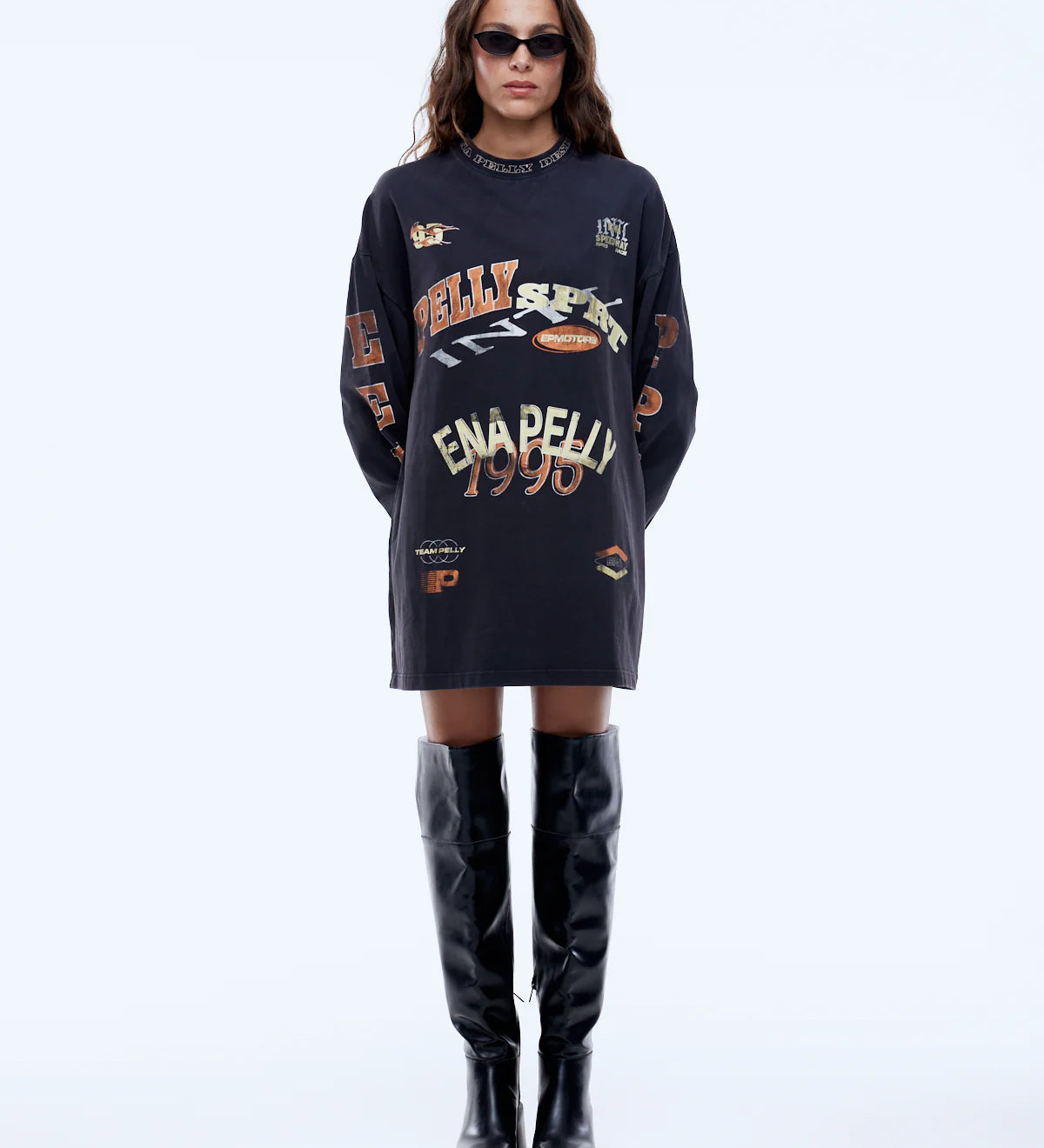 Person wearing a black oversized sweater with text and graphics, paired with black knee-high boots on a white background.