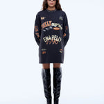 Person wearing a black oversized sweater with text and graphics, paired with black knee-high boots on a white background.