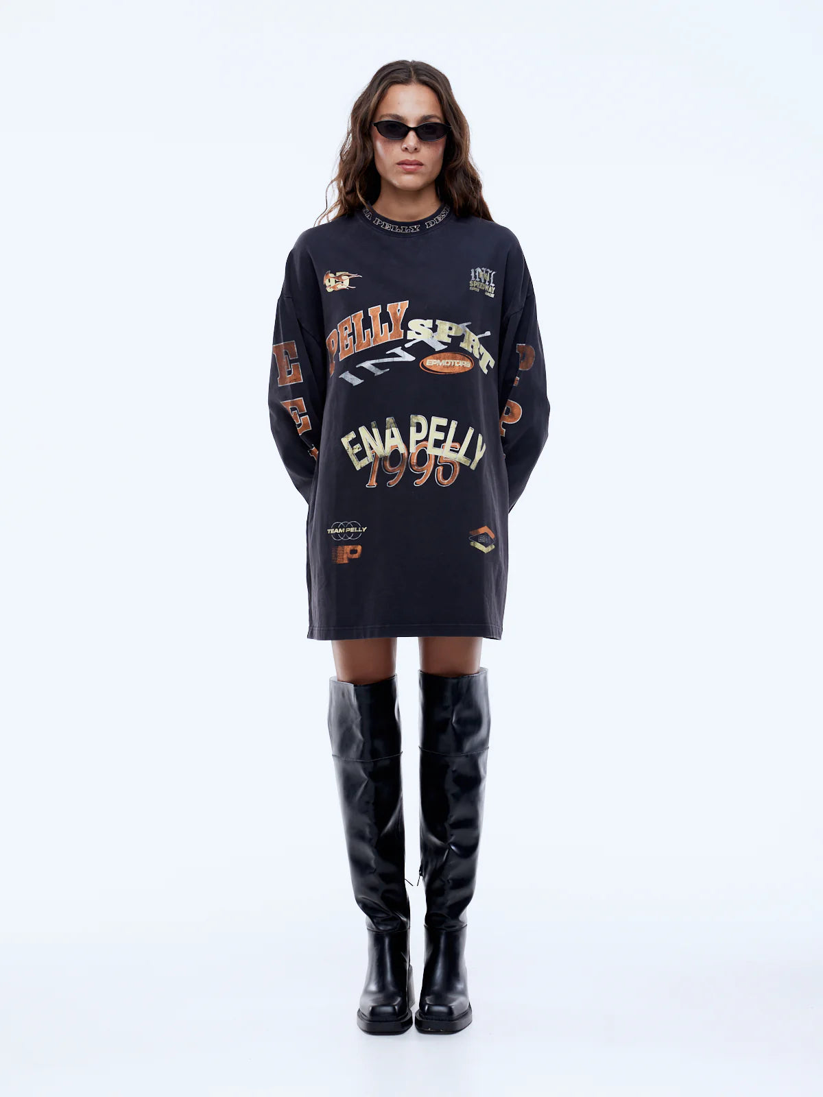 Person wearing a black oversized sweater with text and graphics, paired with black knee-high boots on a white background.