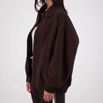 Person wearing a brown jacket and pants on a white background