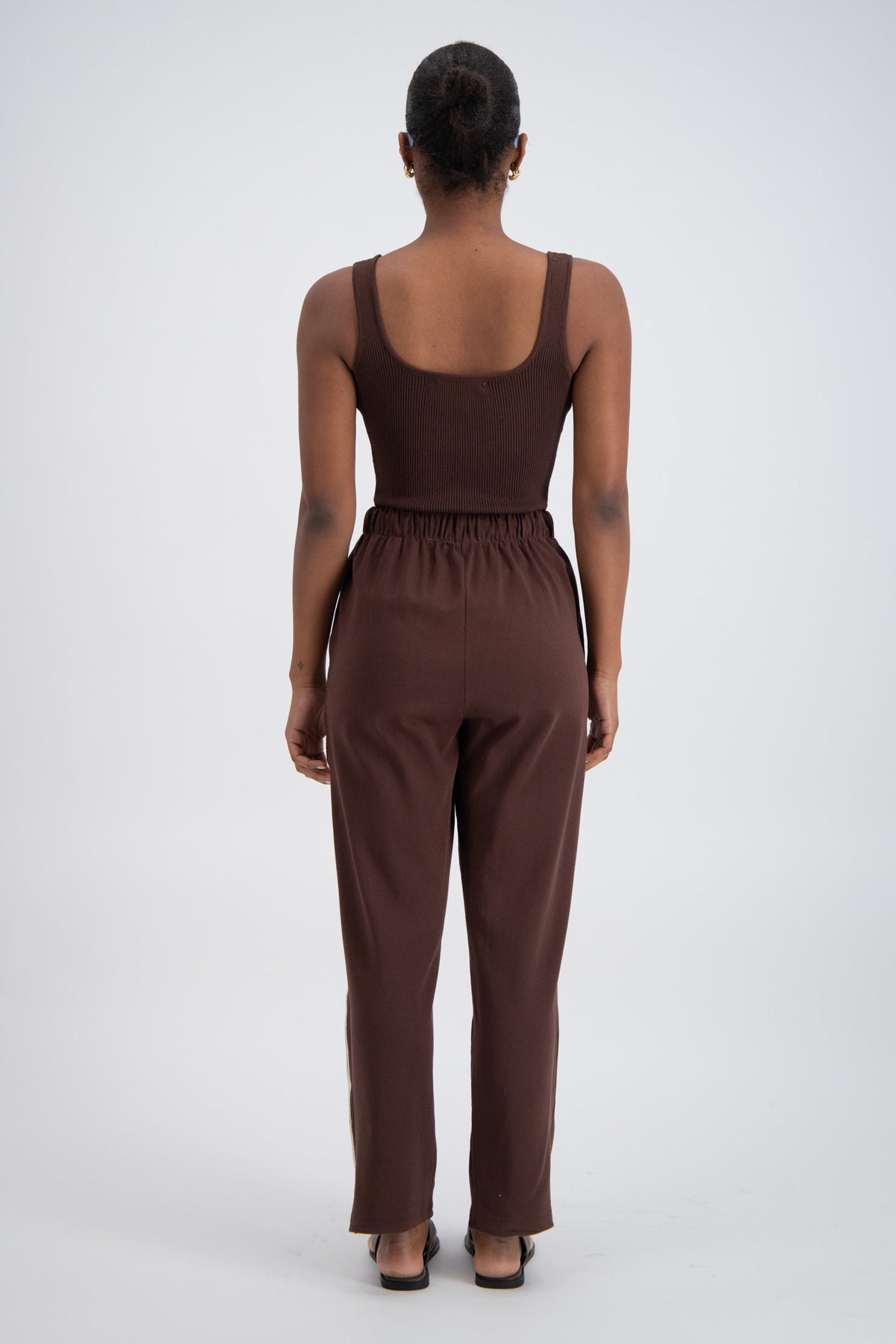 person wearing brown trackpants and a brown top.