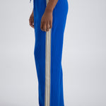 Person standing sideways wearing blue striped trackpants