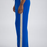 Person standing sideways wearing blue striped trackpants