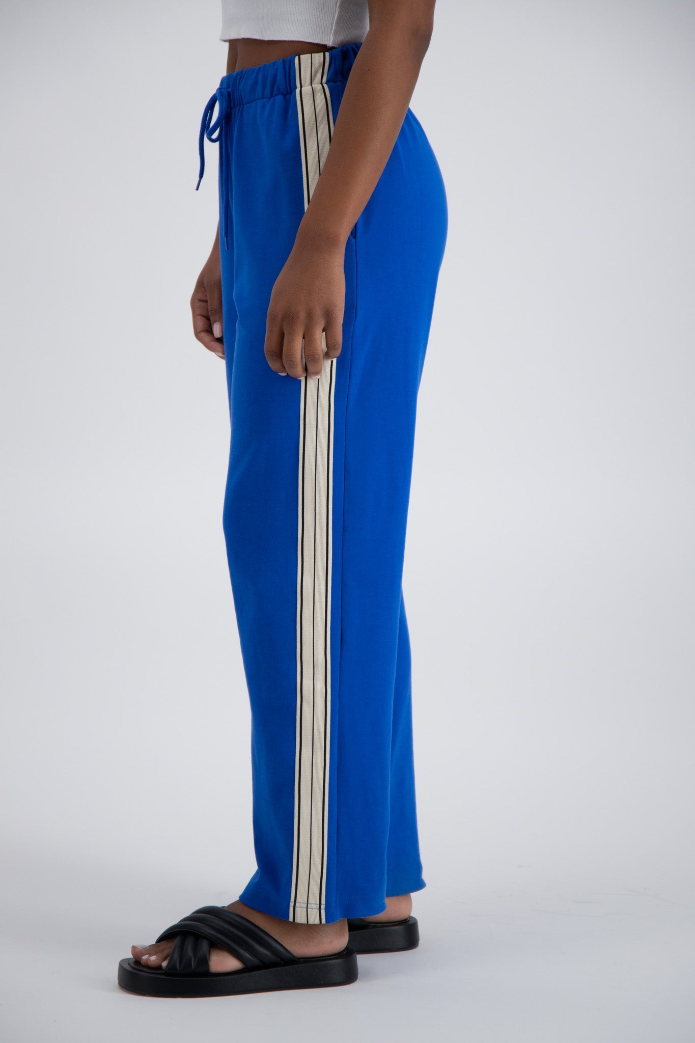 Person standing sideways wearing blue striped trackpants