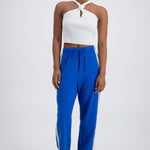 A person wearing cobalt blue trackpants with a relaxed fit, featuring an elastic waistband with drawstring and pockets.