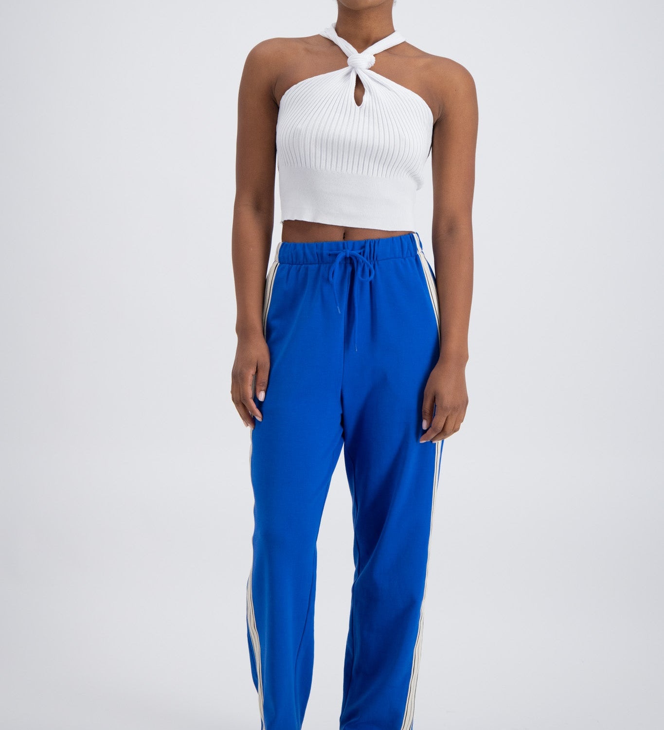 A person wearing cobalt blue trackpants with a relaxed fit, featuring an elastic waistband with drawstring and pockets.
