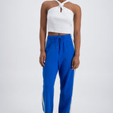 A person wearing cobalt blue trackpants with a relaxed fit, featuring an elastic waistband with drawstring and pockets.
