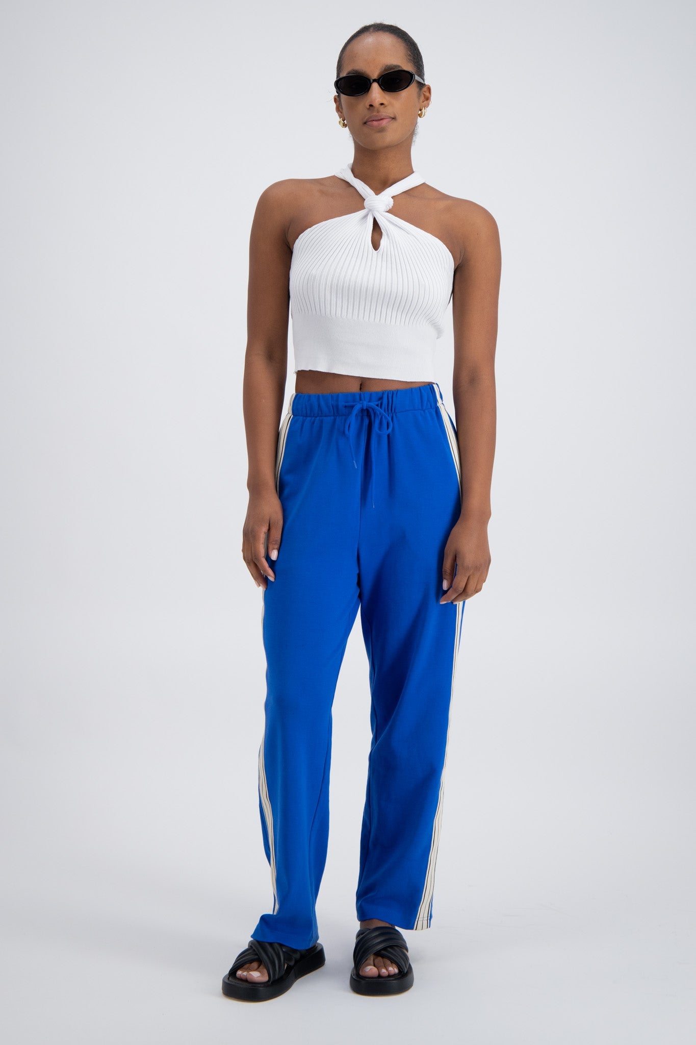 A person wearing cobalt blue trackpants with a relaxed fit, featuring an elastic waistband with drawstring and pockets.