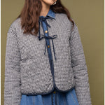 Woman wearing a checkered jacket and blue jeans against a brown background